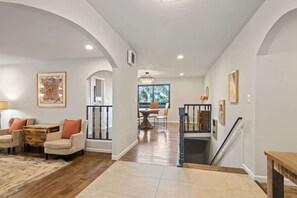A spacious living area with a wooden floor, a dining table, and a staircase leading to an upper level. - @ Marbella Lane- Perfect Blend of Scenic & Comfort (Colma)