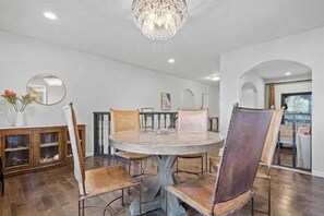 A dining area with a round table and chairs, a chandelier, and a wooden cabinet with glass doors. - @ Marbella Lane- Perfect Blend of Scenic & Comfort (Colma)
