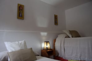 Una habitación de hotel con dos camas, una mesita de noche con lámpara y dos cuadros colgados en la pared.