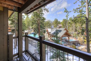 A wooden deck with a view of a resort area including a pool, cabins, and surrounding trees. - Inner Circle 12 in Columbine Rd (Columbine Rd)