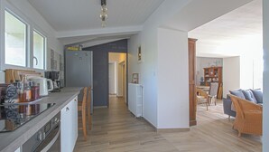 Eine moderne Küche mit einer zentralen Kochinsel, Holzstühlen und einem Essbereich mit Korbmöbeln.