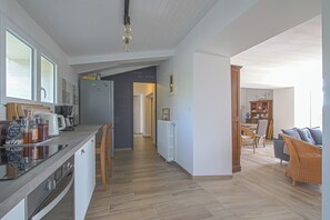 Une cuisine moderne dotée d’un îlot central, de chaises en bois et d’un coin repas avec des meubles en osier.