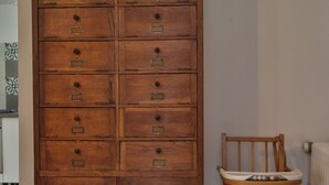 Ein Holzschrank mit mehreren Schubladen und ein hölzerner Hochstuhl daneben.