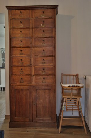 Un meuble en bois avec plusieurs tiroirs, et à côté, une chaise haute en bois.