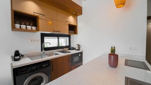Cocina compacta con lavavajillas, microondas y pileta. Cuenta con muebles de madera y una encimera.