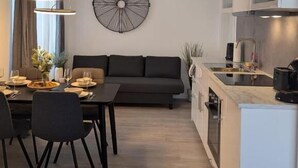 Ett modernt kök med en central köksö, en matplats med en mörk soffa och ett stort konstverk på väggen.