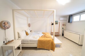 Een moderne slaapkamer met een hemelbed, nachtkastjes, een bedlampje, een boekenkast en een radiator.