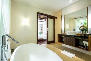 Ein modernes Badezimmer mit Badewanne, Waschtisch mit Spiegel und Duschbereich.