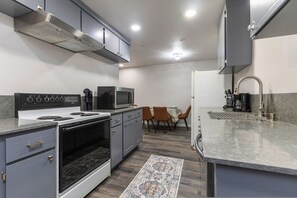 A modern kitchen with a built-in microwave, stove, and oven. There is a dining area with a table and chairs.