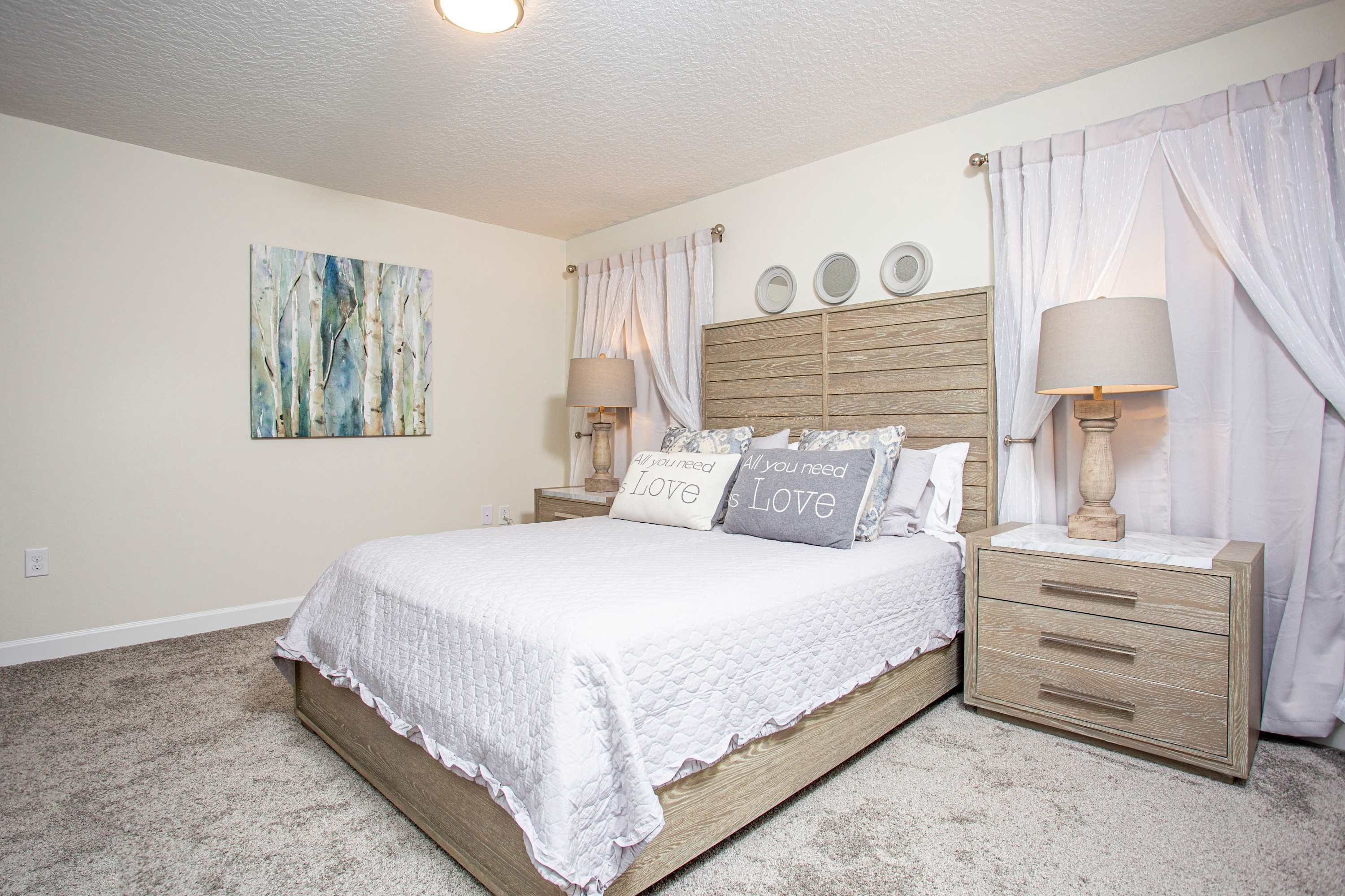 A bedroom with a bed, two nightstands, a headboard, and a painting on the wall.
