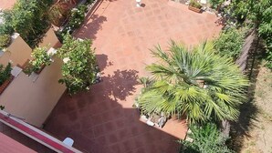 A courtyard with a tiled floor, surrounded by a red metal fence, and various potted plants. - Vacation home Sorrento Peninsula (Vico Equense)