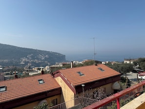 Eine Küstenstadt mit terrakottafarbenen Dächern, einer markanten Antenne und Blick aufs Meer.