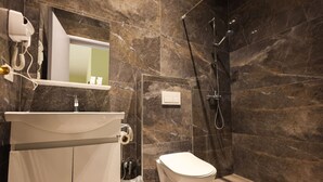 A modern bathroom with a marble wall, a white sink, a toilet, and a shower area. - Azzurra Studio 03 in Durrës (Durrës)