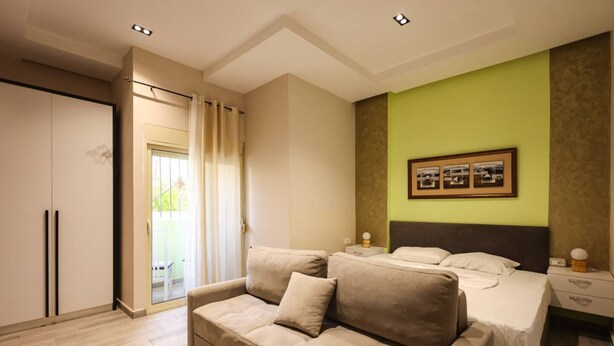 A bedroom with a sofa, a bed, a nightstand, and a framed picture on the wall. - Azzurra Studio 01 in Durrës (Durrës)
