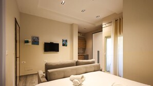 A hotel room with a bed, a sofa, a television, and a window with curtains. - Azzurra Studio 01 in Durrës (Durrës)