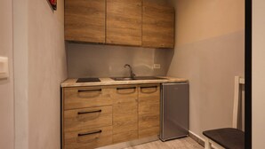 A compact kitchen with wooden cabinets, a sink, and a small refrigerator. - Azzurra Studio 01 in Durrës (Durrës)