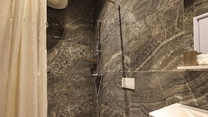 A bathroom with a shower, marble walls, and a toilet. - Azzurra Studio 01 in Durrës (Durrës)