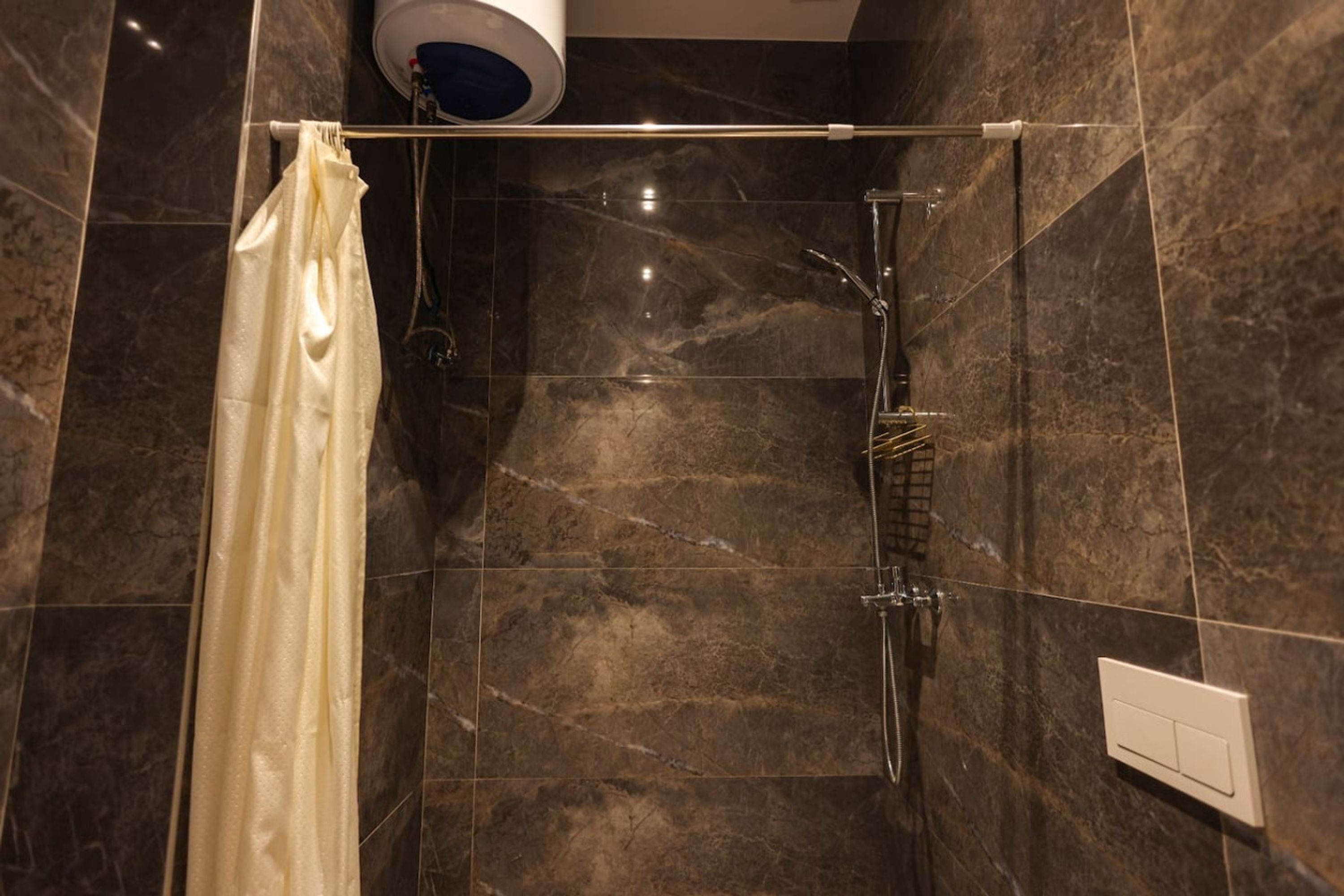 A shower area with a glass door, a towel rack, and a control panel on the wall.