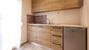Een keuken met houten kastjes, een achterwand van baksteen en een roestvrijstalen koelkast.