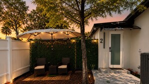 Une terrasse avec deux chaises, une table et un parasol.