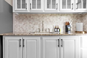A kitchen with white cabinets, a marble backsplash, and a stainless steel sink. - 3rd Floor Condo~ Tower Isle~24hr Security (Tower Isle)