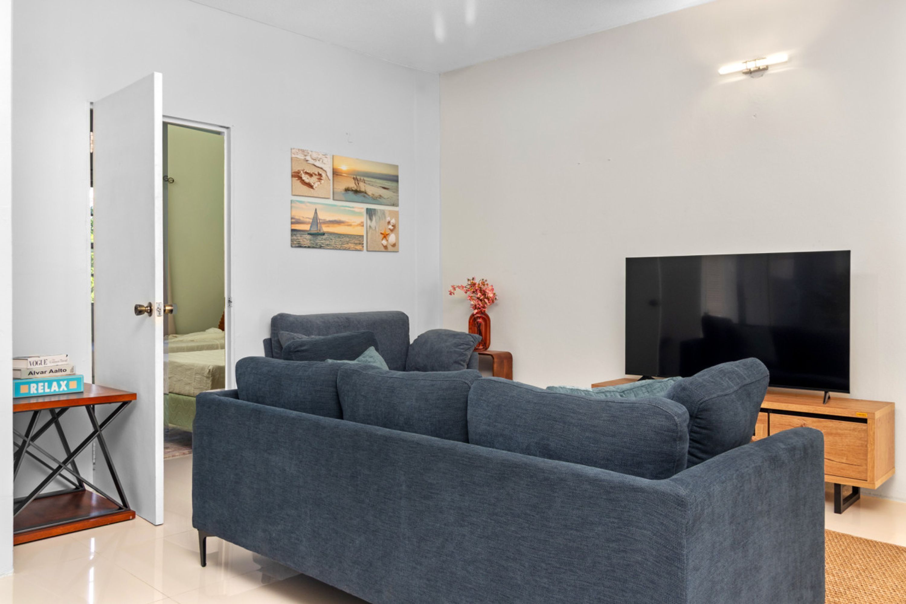 A modern living room with a grey sofa, a flat-screen TV, and a wooden side table.