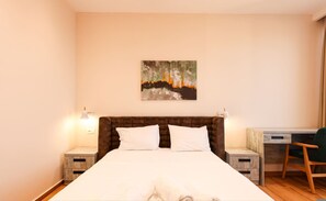 Een slaapkamer met een groot bed, twee nachtkastjes, een bureau en een stoel.