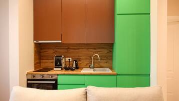 Una cucina compatta con schienale in legno, piano di lavoro verde e lavello.