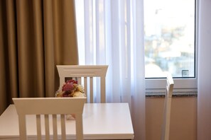 Ein weißes Tisch- und Stuhlgarnitur in einem Zimmer mit Fenster und Vorhängen.