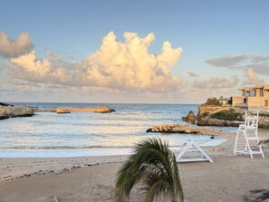 A beach with a clear sky, rocky outcrops, and a white structure with a ladder. - Sun-Soaked Paradisiac Escape|3BR, Private Beach, Pool (Plantation Village)