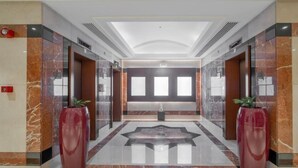 A modern lobby with marble flooring, large red vases, and a central seating area. - Majestic Premier Hotel Bur Dubai (Dubai)
