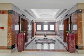 A modern lobby with marble flooring, large red vases, and a central seating area. - Majestic Premier Hotel Bur Dubai (Dubai)