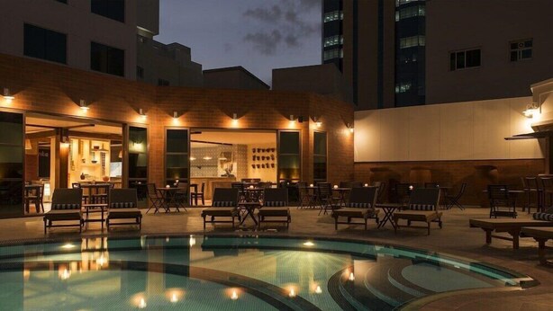 A poolside area with lounge chairs, a bar, and a pool. - Majestic Premier Hotel Bur Dubai (Dubai)