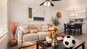 Un saló modern amb un sofà, una taula de centre amb una pilota de futbol, espelmes i una estàtua decorativa daurada.