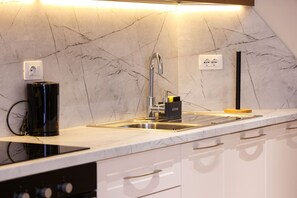Een moderne keuken met een marmeren achterwand, een roestvrijstalen spoelbak en een zwarte koffiezetapparaat.
