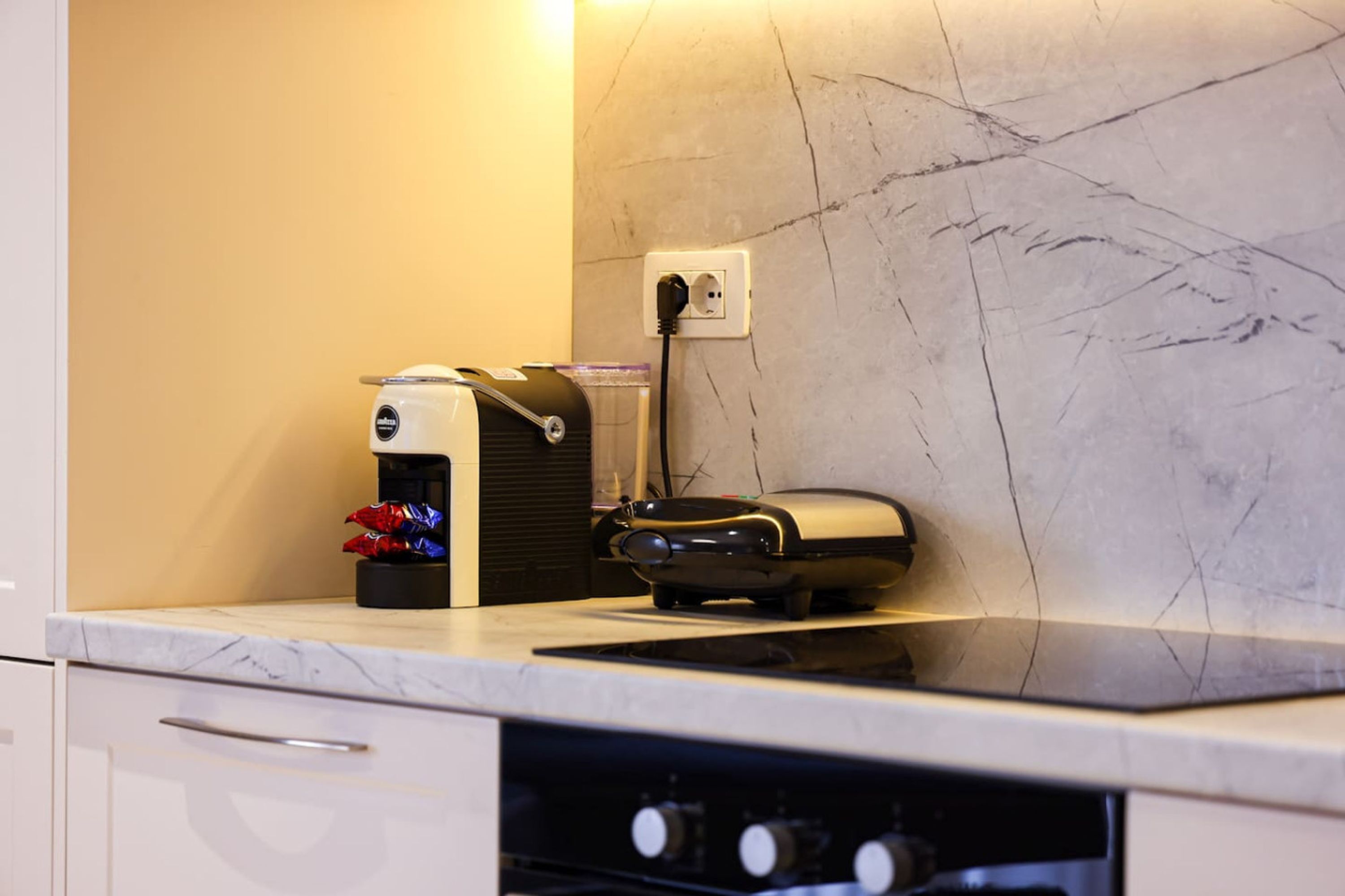 A kitchen with a coffee maker, a toaster, and a power outlet on the countertop.