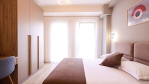 Una habitación de hotel moderna con una cama grande, un escritorio y un armario.
