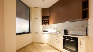 Una cocina compacta con armarios blancos, horno integrado y ventana.