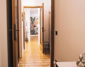 A hallway with wooden flooring leading to a room with a large plant mural. - RR | Casa Aquilani | Lakeview | Lago di Garda (Toscolano Maderno)
