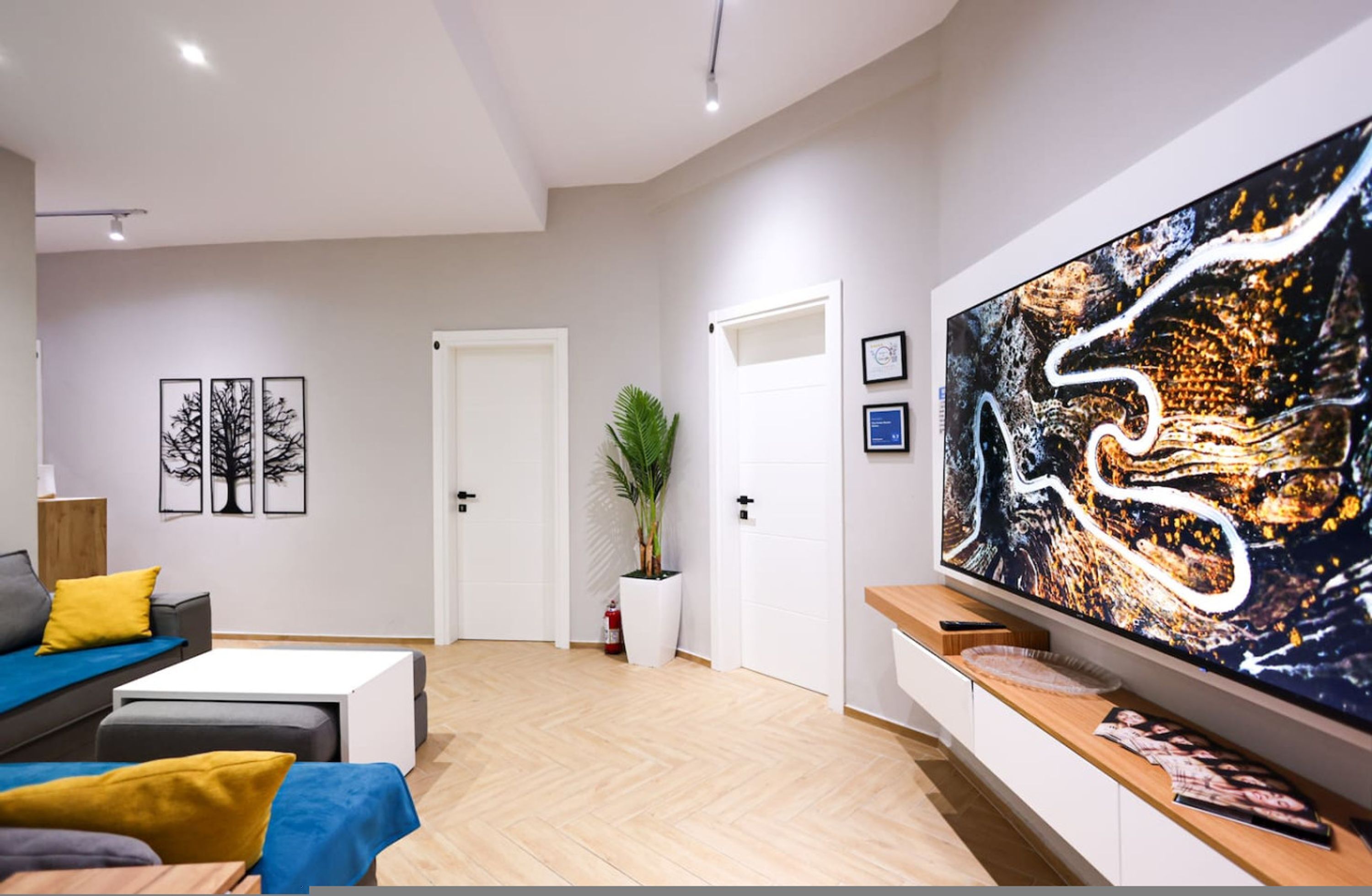 A modern living room with a large abstract painting, a sofa set, a coffee table, and a TV on a wooden stand.