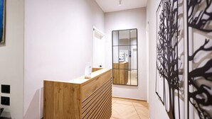 Ein moderner Empfangsbereich mit einem Holzboden, einem großen Spiegel und einer Wanddekoration.