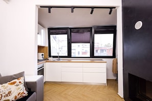 A compact kitchen with a window, white cabinets, and a herringbone floor. - Grandstay Central in Durrës (Durrës)