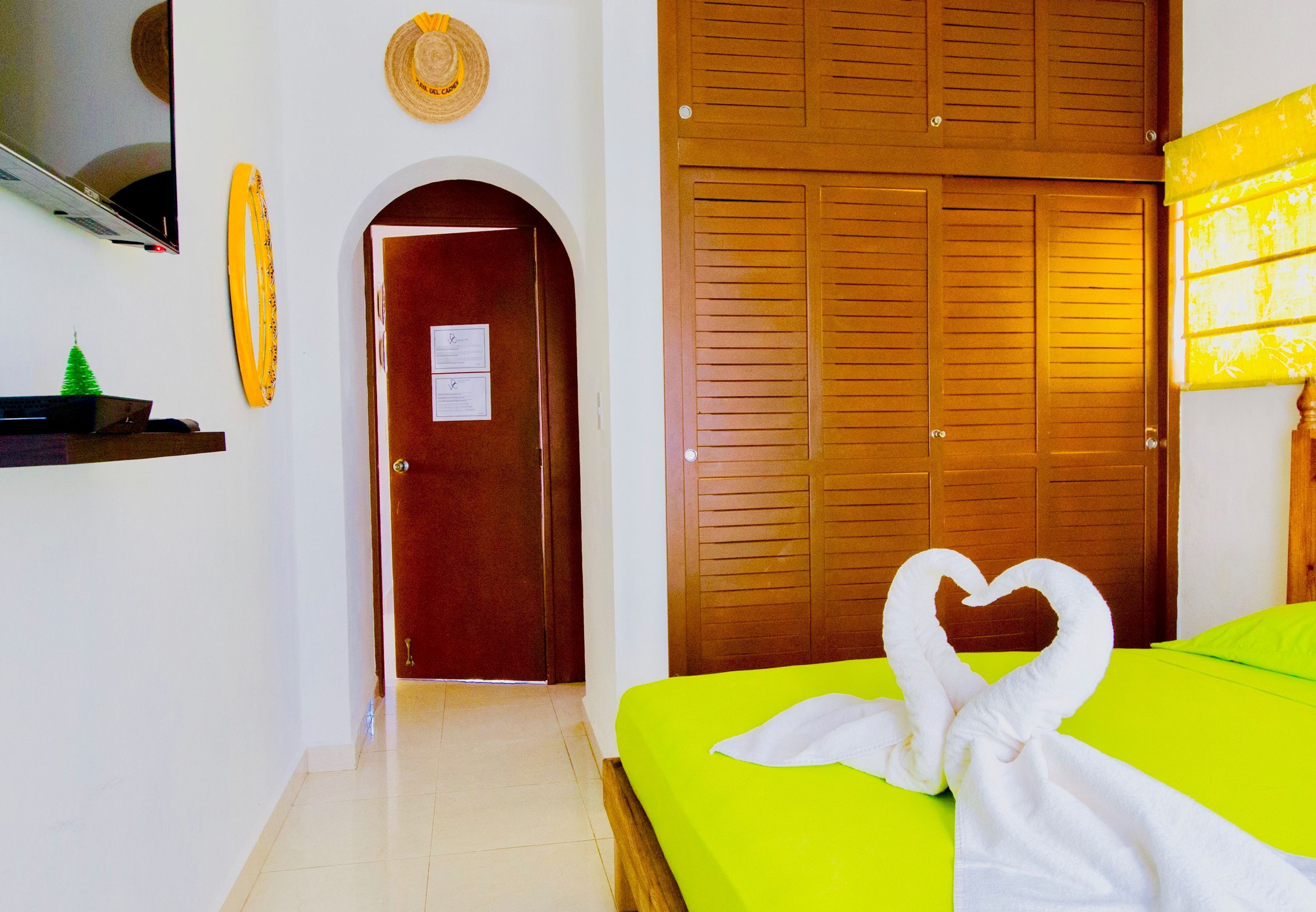 A hotel room with a bed, a wooden door, and a small green Christmas tree.