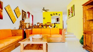 A living room with orange sofas, wooden coffee table, and a ceiling fan. - Camera superior standard (Playa del Carmen)