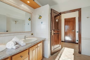 A bathroom with a sink, mirror, towel, and wooden cabinets. - Il Borgo del Vergante Apartments (Nebbiuno)