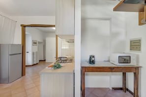 A kitchen with a refrigerator, stove, microwave, and a wooden table. - Il Borgo del Vergante Apartments (Nebbiuno)