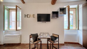 Una habitación con televisión, una mesa con sillas y un cartel con la palabra 'HOME' en la pared.