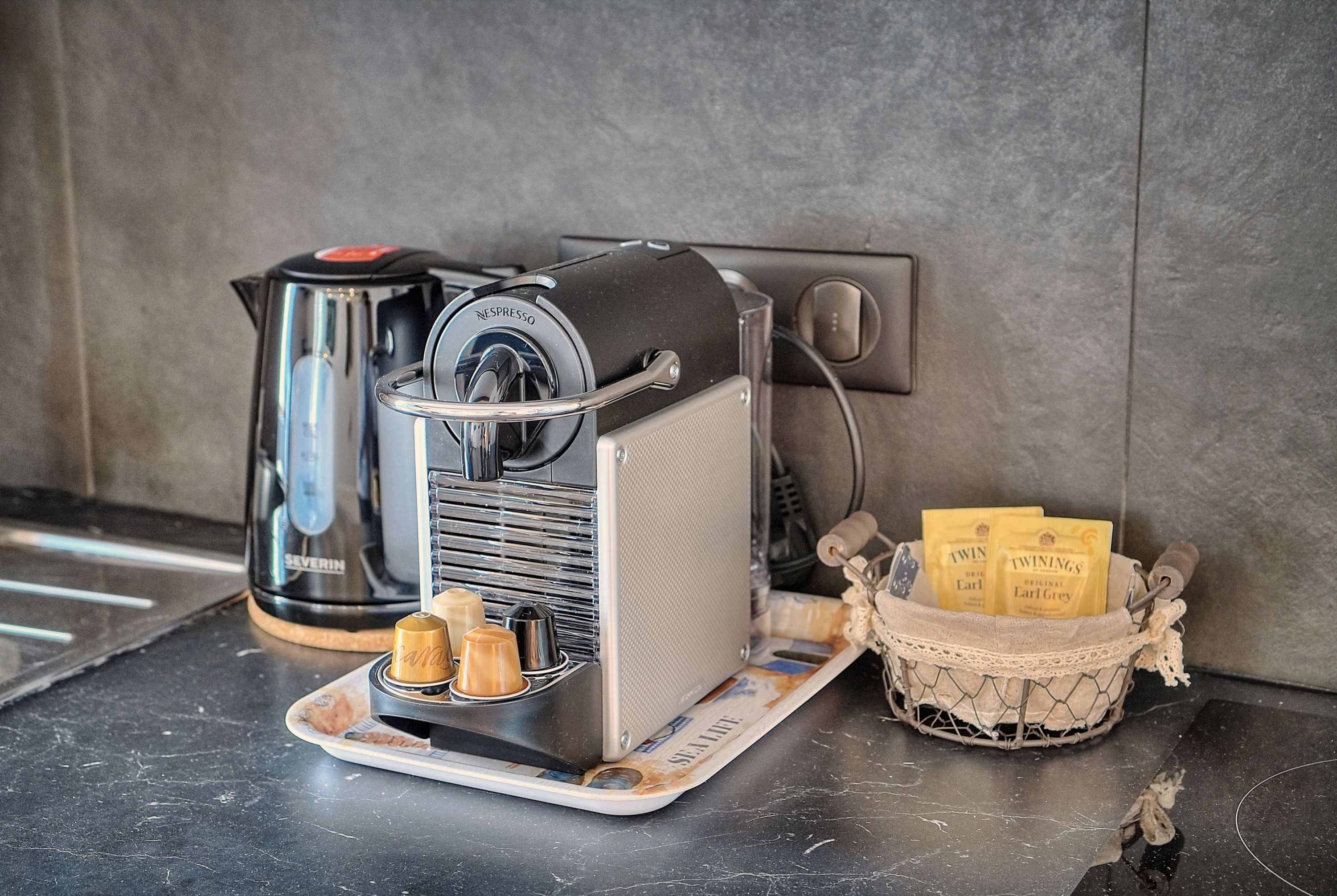 Eine Kaffeemaschine mit Milchaufschäumer, einer Kaffeekanne und einer Schale mit Kaffeekapseln.