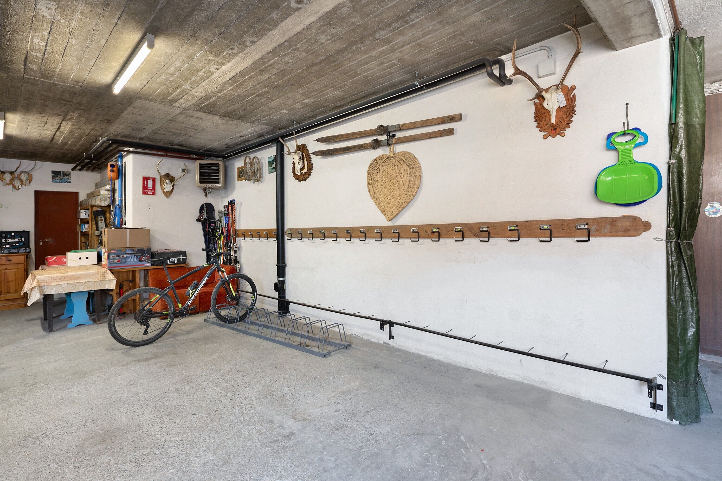 Un garage contenant un vélo, des crochets fixés au mur et divers outils.