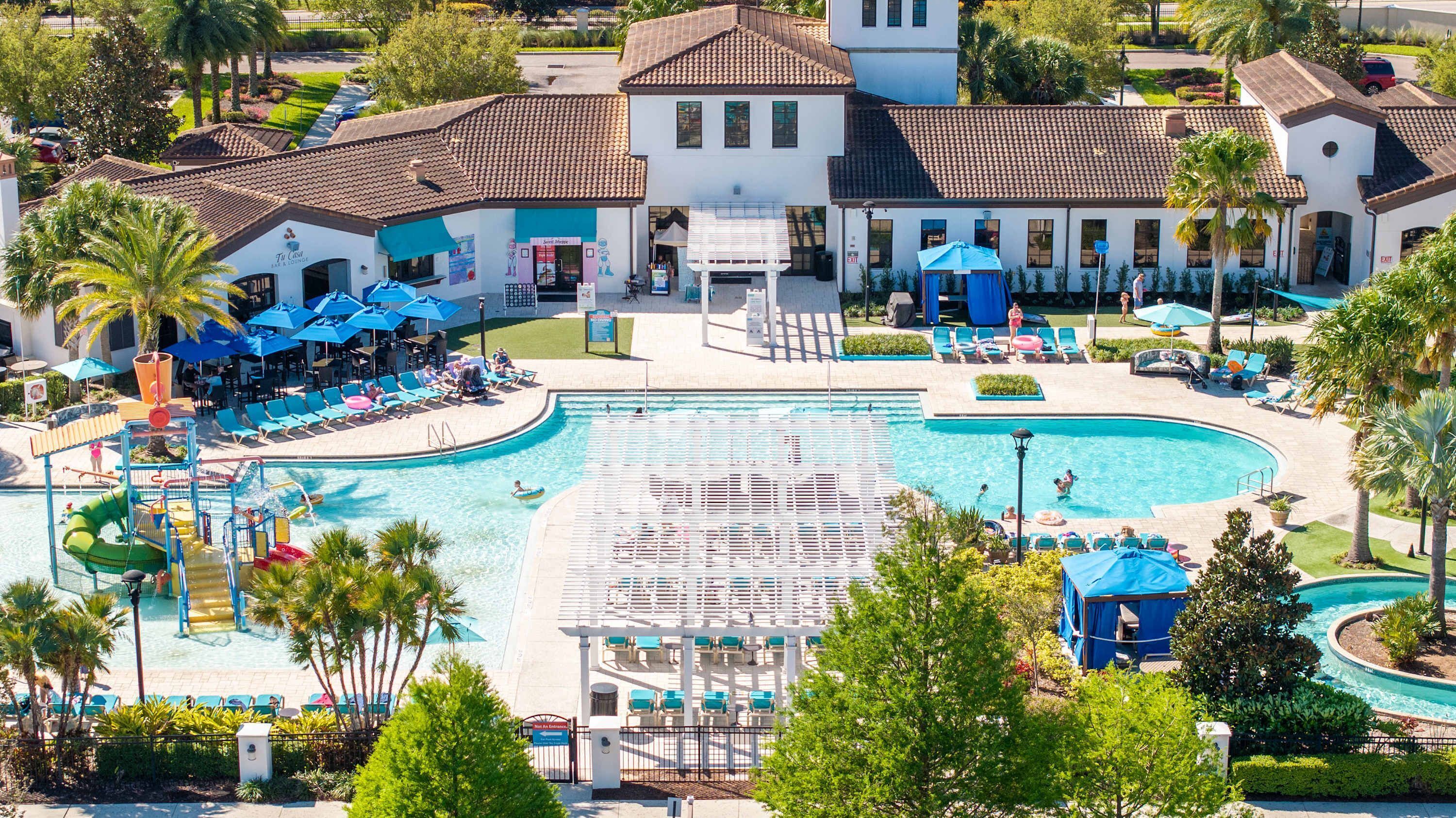 A resort with a large pool, lounge chairs, and a building with a tiled roof.